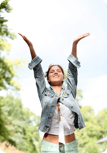 woman smiling with arms raised outdoors, representing improved confidence and mental health after therapy